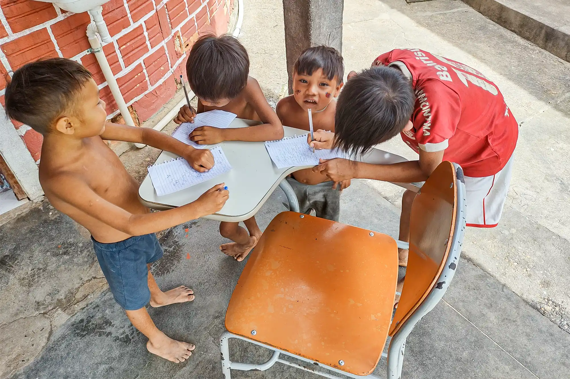 Marico (de camisa do Internacional), filho de Ifioma, e seus amigos brincam com as canetas e as folhas de papel da reportagem de Radis. — Foto: Luiz Felipe Stevanim.