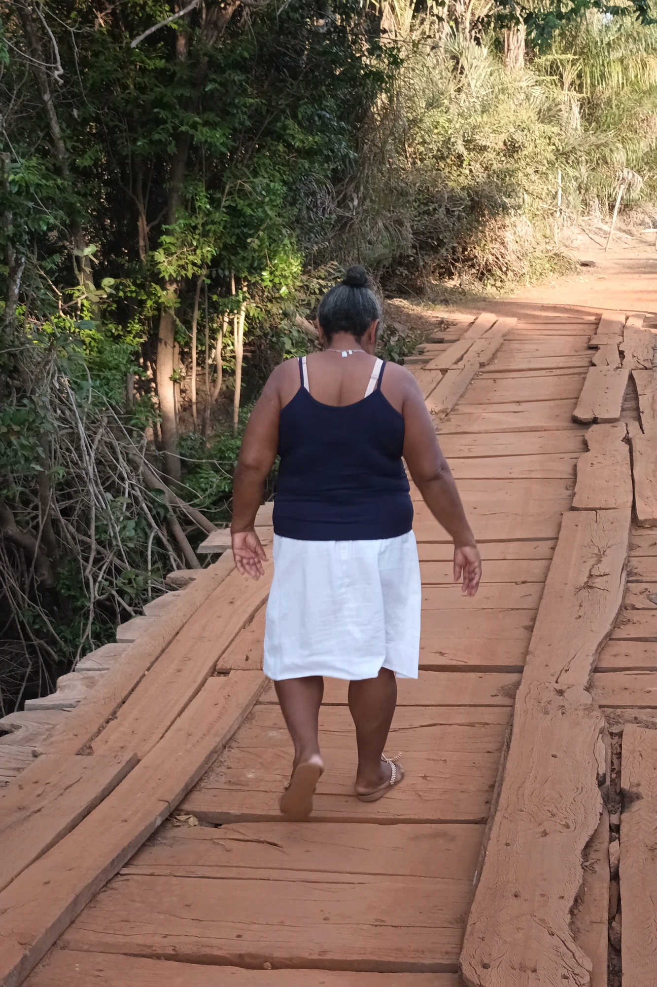 Dona Rosário sobre a ponte improvisada: desafio para a comunidade. — Foto: Ana Cláudia Peres.