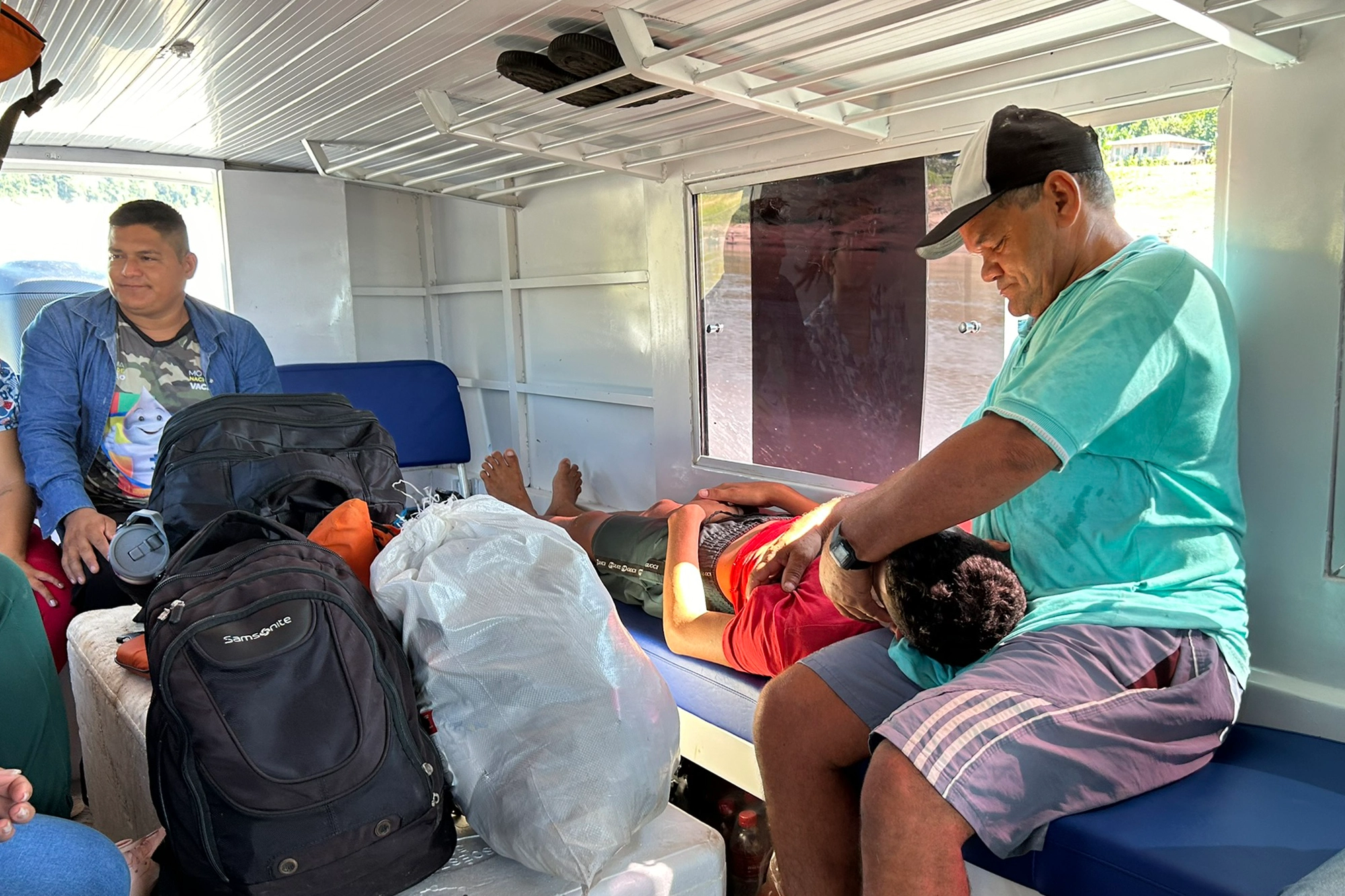 Ribeirinhos aproveitam a presença das equipes de saúde para socorrer de Denilson Martins, que é levado ao barco; no detalhe, o rapaz já a bordo, no colo do pai, Raimundo Alves. — Foto: Adriano De Lavor.