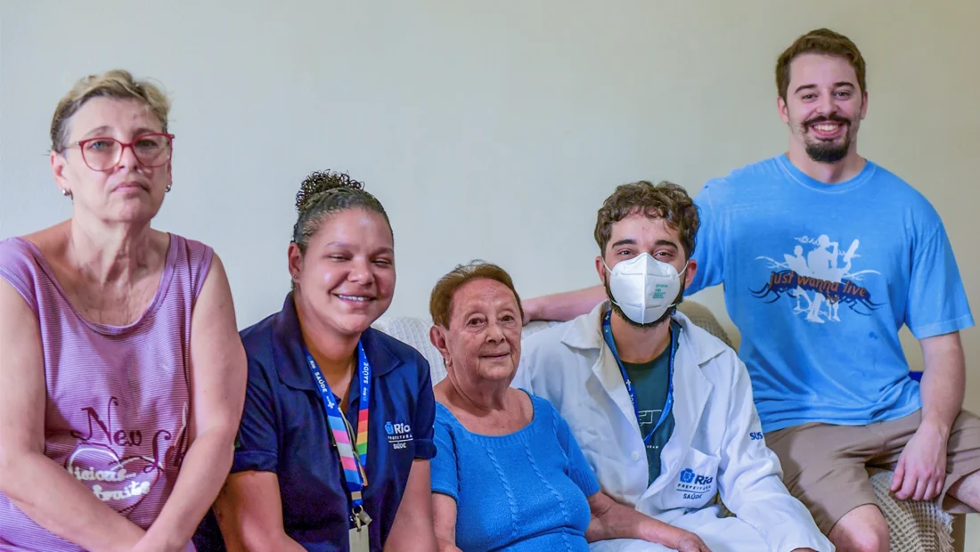 Em família: Dona Nadir, 89 anos, recebe em sua casa a equipe da ESF com a ACS Thaís Villela e o médico residente Marcos Herkenhoff, ao lado da nora Mônica e do neto Lucas. — Foto: Fernanda Andrade.