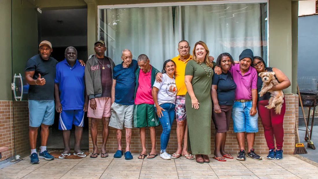 Paulo Francisco, Denir, Paulo Pinheiro, Benedito, Claudemiro, Fabiana, Luiz Carlos e o cachorro Floquinho são moradores de uma residência terapêutica; ao lado dos cuidadores e da coordenadora de saúde mental do Carmo (RJ), Érica Victório, mostram que o cuidado em liberdade é transformador. — Foto: Eduardo de Oliveira.